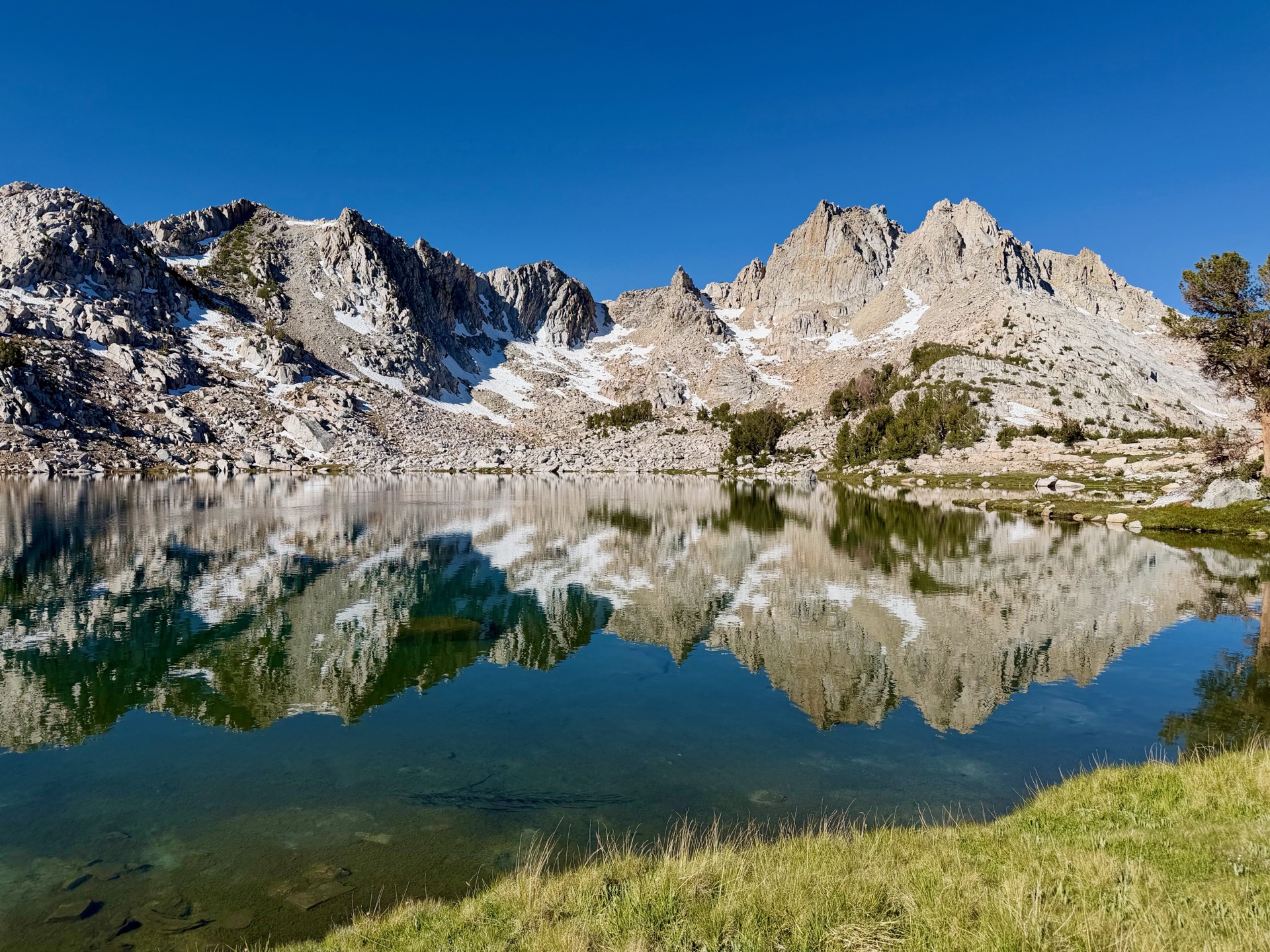 Jagged granite peaks reflected in a clear alpine lake along the Silver Divide