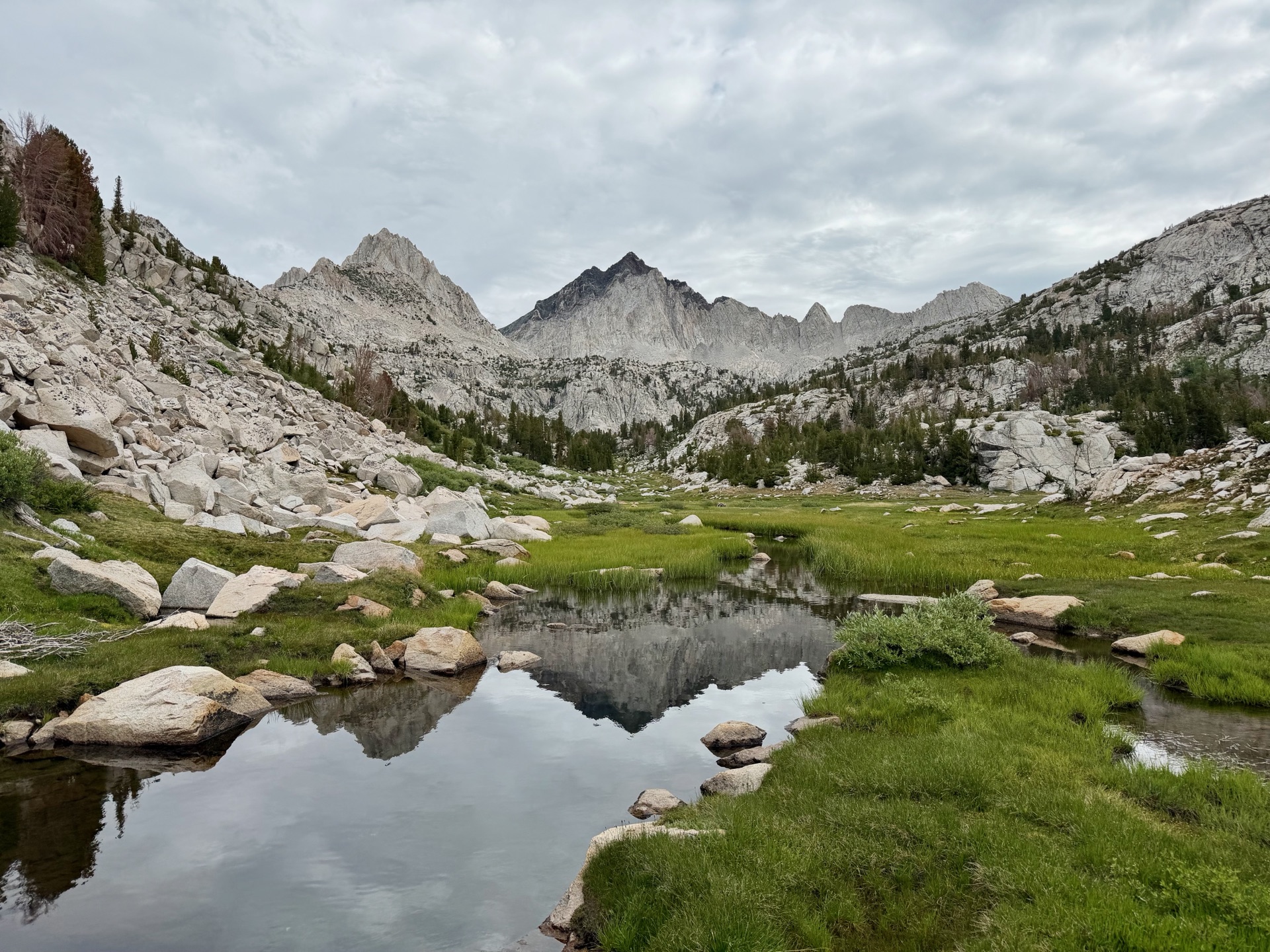 Granite peaks above a reflective meadow pool along the Dragonscar Traverse